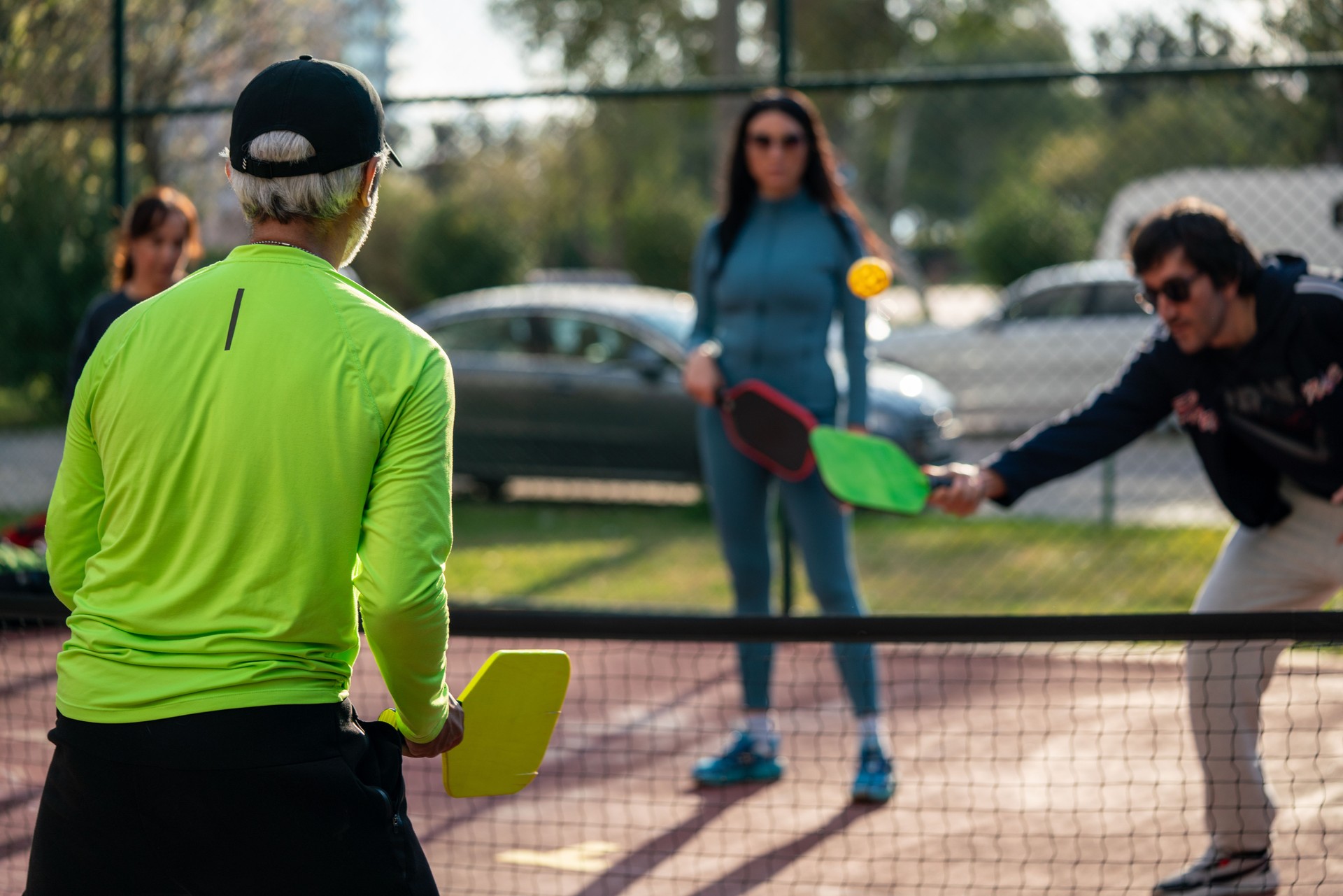 senior man coach is teaching pickleball on hardcourt horizontal still