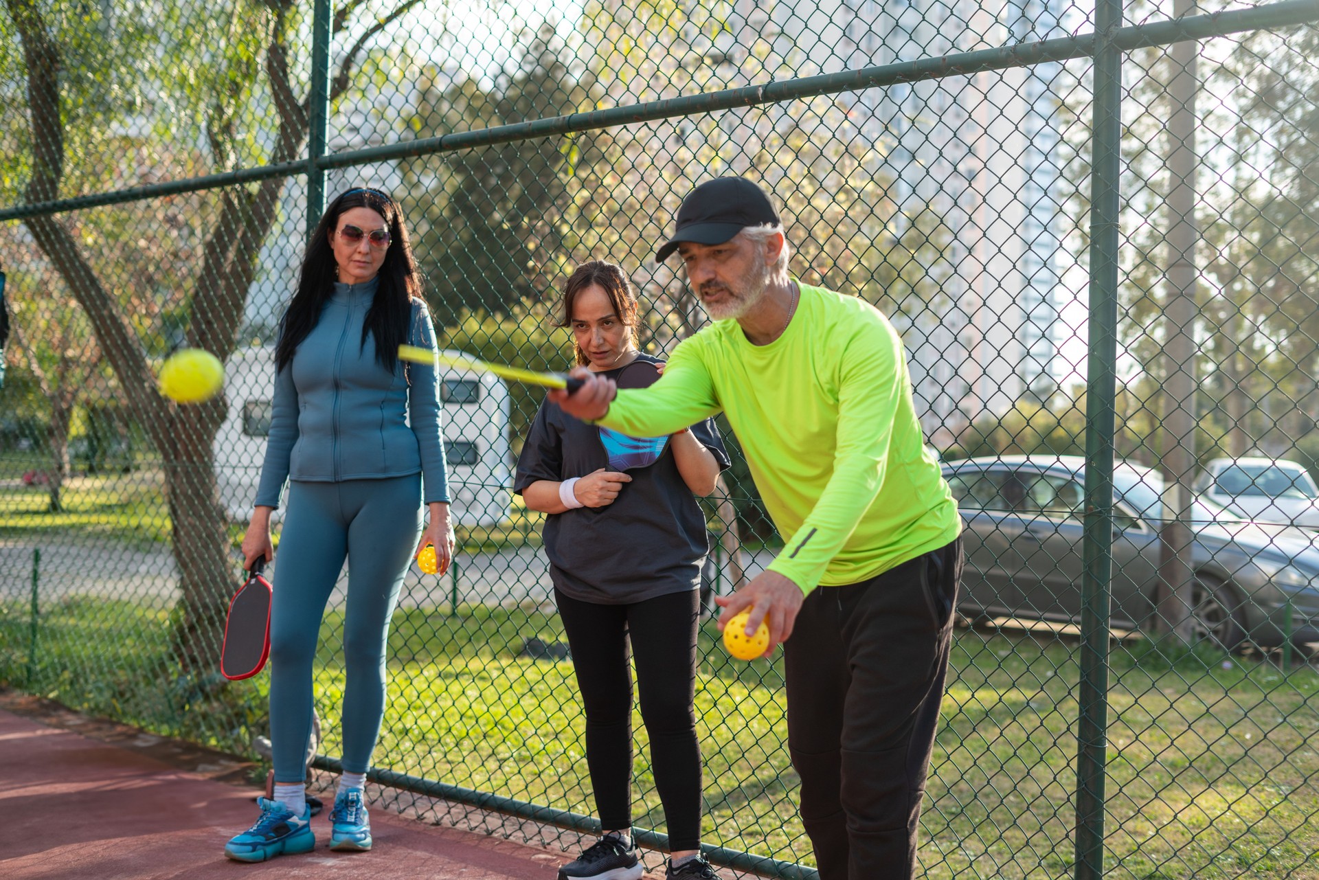 senior man pickleball coach is teaching how to play to two senior woman pickleball player horizontal pickleball still