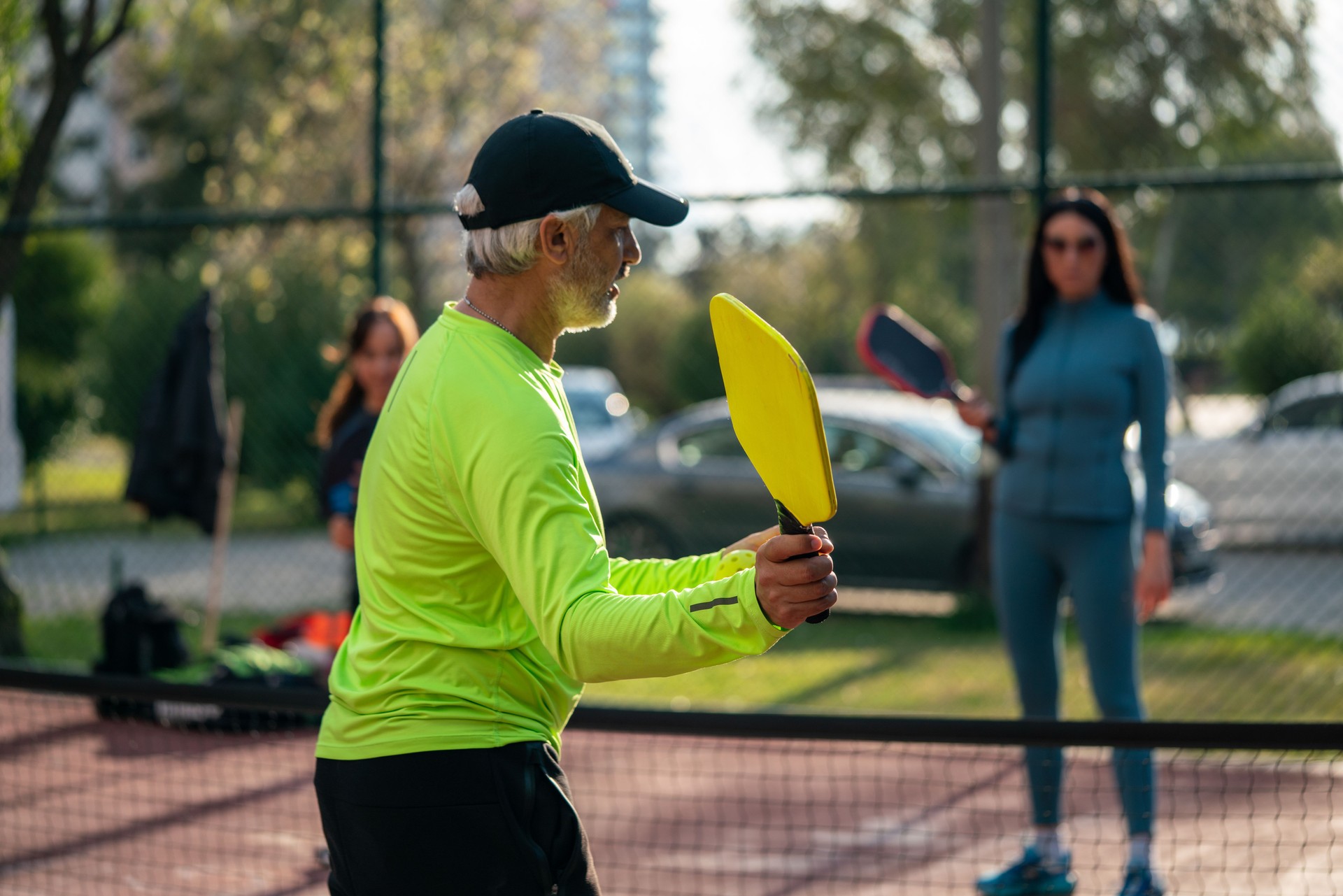 senior man pickleball coach is teaching forehand two woman pickleball player horizontal pickleball still