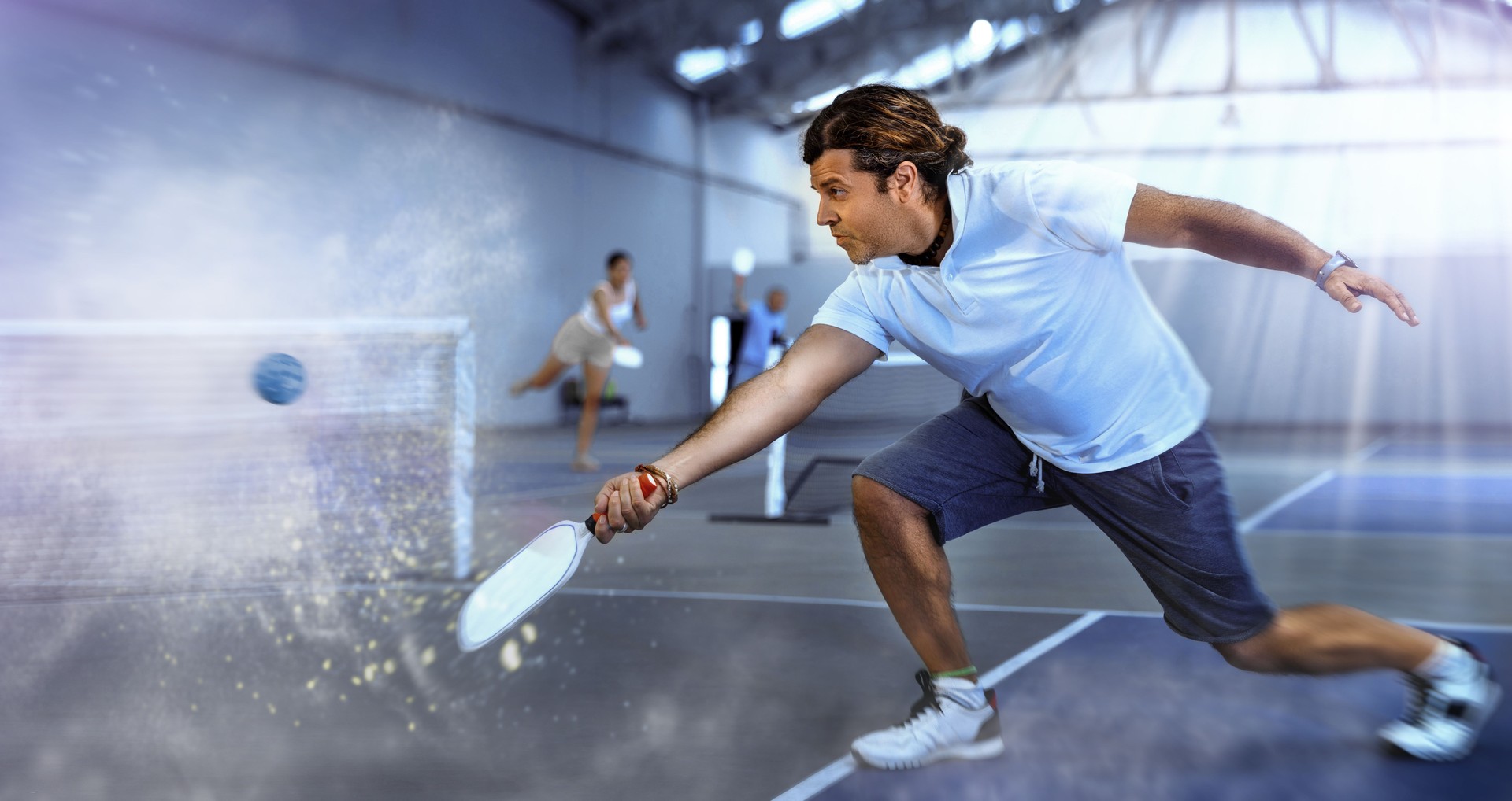 Sporty man pickleball tennis player trains on the indoor court using a racket to hit ball